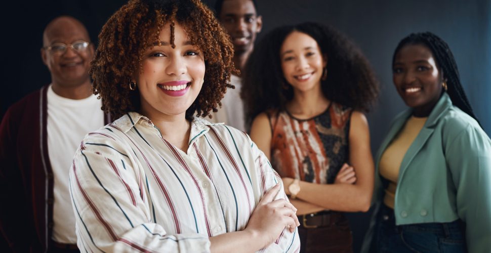 Portrait, collaboration or leadership with a business black woman manager standing arms crossed with her team in a studio. Teamwork, management or trust with a female leader and her employee group